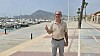 Diego Coello Beltrán står på havnepromenaden i Altea med tommelen opp. Båter i marinaen og fjell i bakgrunnen.