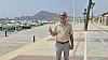 Diego Coello Beltrán står på havnepromenaden i Altea med tommelen opp. Båter i marinaen og fjell i bakgrunnen.